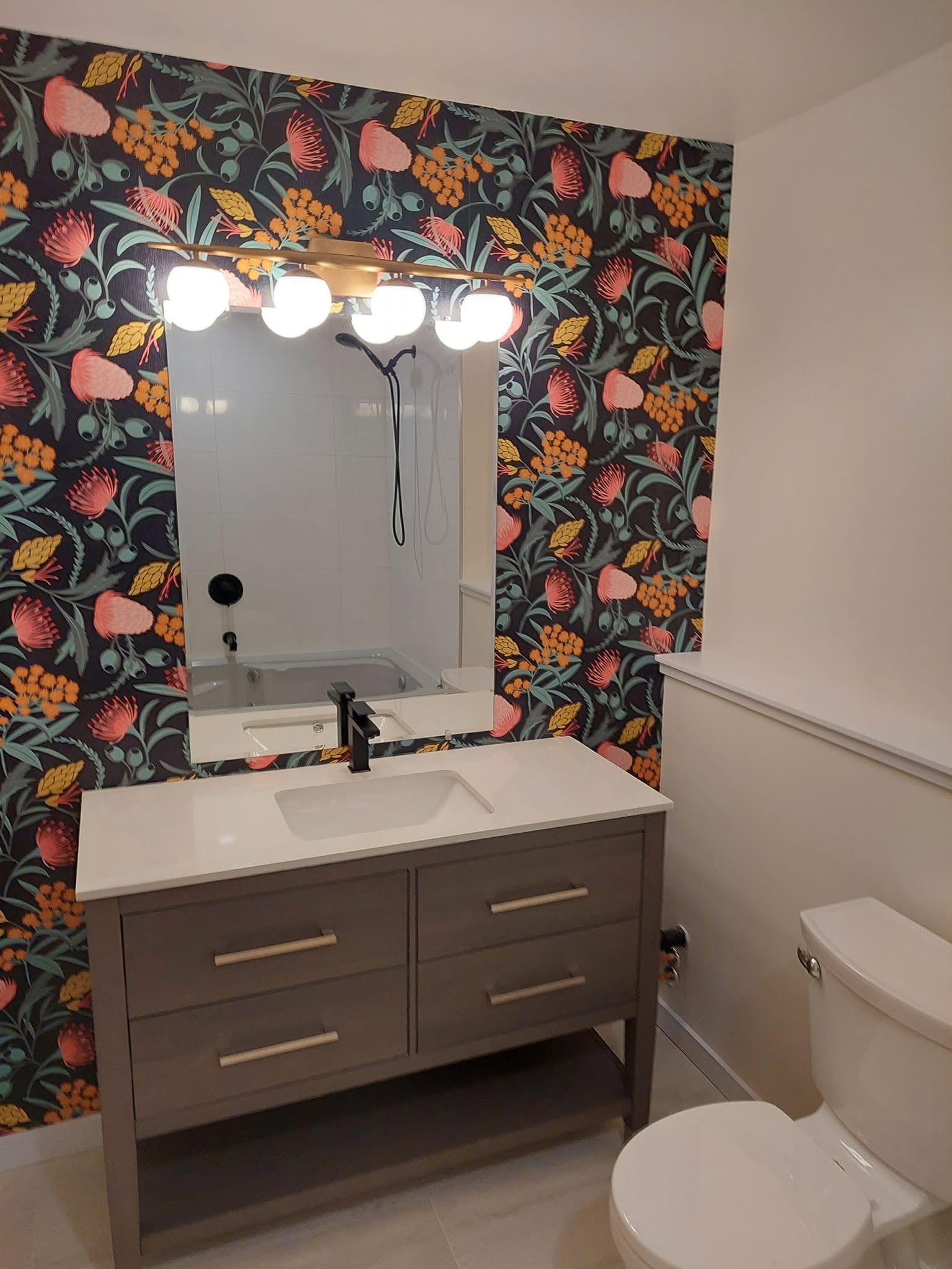 Bathroom renovation — bold floral wallpaper, vanity, gold light fixture