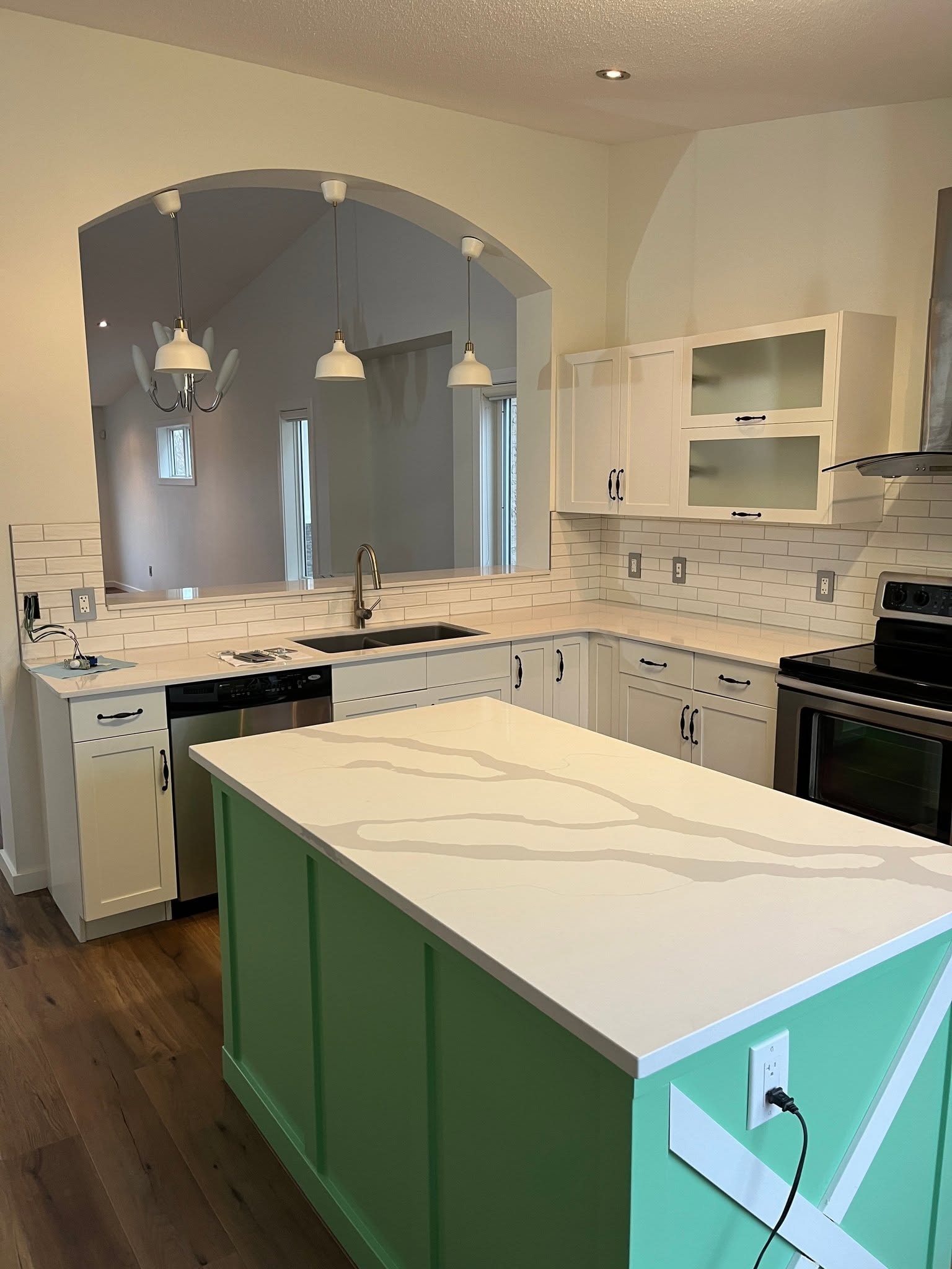 Kitchen renovation — green island, white cabinetry, arched pass-through