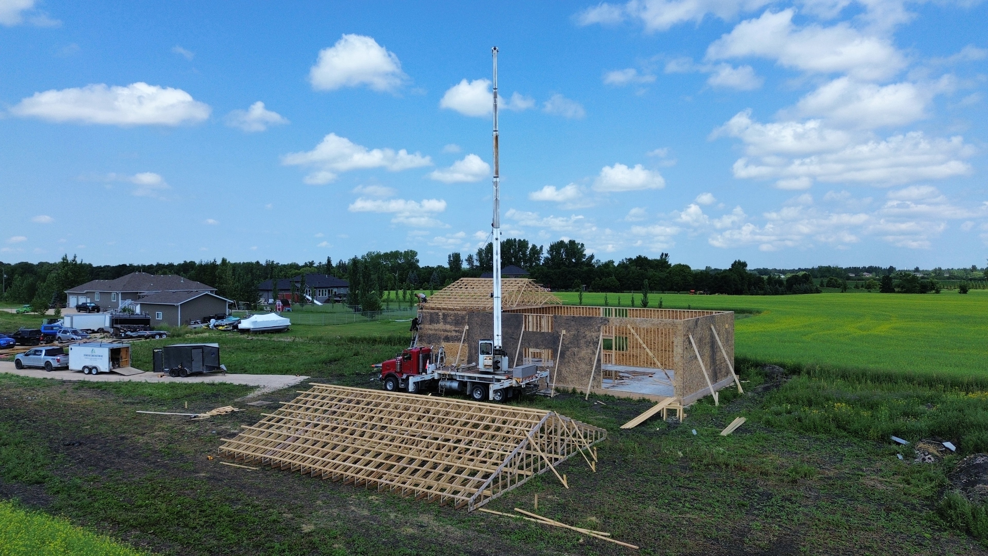 Rural shop build — aerial view, crane and crew framing large shop structure